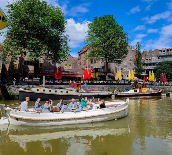De open rondvaartboot The Dream vol gasten in de Oude Haven, zwaaiend vanaf het water