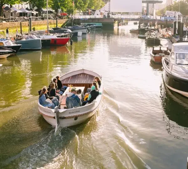De open rondvaartboot The Dream vol gasten vaart door de Wijnhaven in Rotterdam